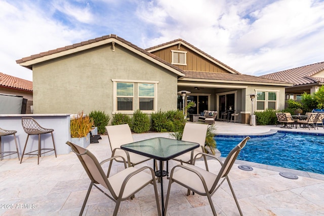 outdoor pool featuring outdoor dining space, ceiling fan, outdoor dry bar, and a patio area