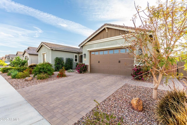 view of front of house featuring driveway, an attached garage, a tile roof, and stucco siding