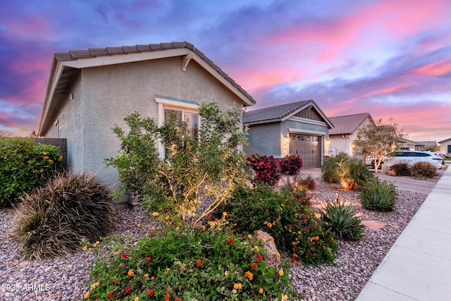 view of front of house with driveway, an attached garage, a tiled roof, and stucco siding