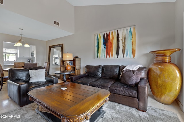 tiled living room featuring a chandelier and high vaulted ceiling