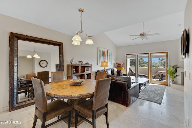 tiled dining room with ceiling fan with notable chandelier and lofted ceiling