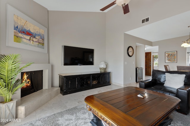 living room with high vaulted ceiling, ceiling fan, a tile fireplace, and tile floors