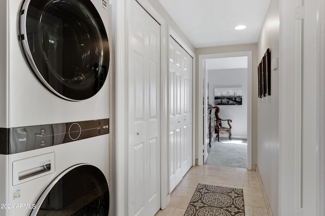 clothes washing area with stacked washer and dryer and light tile floors