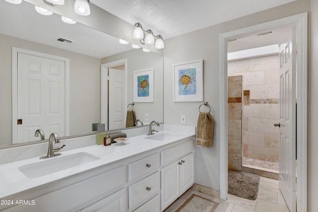 bathroom featuring a textured ceiling, dual bowl vanity, and tile flooring