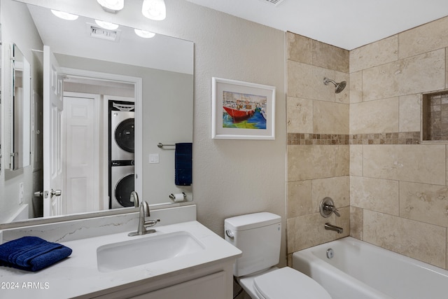 full bathroom featuring vanity, toilet, tiled shower / bath combo, and stacked washer / drying machine