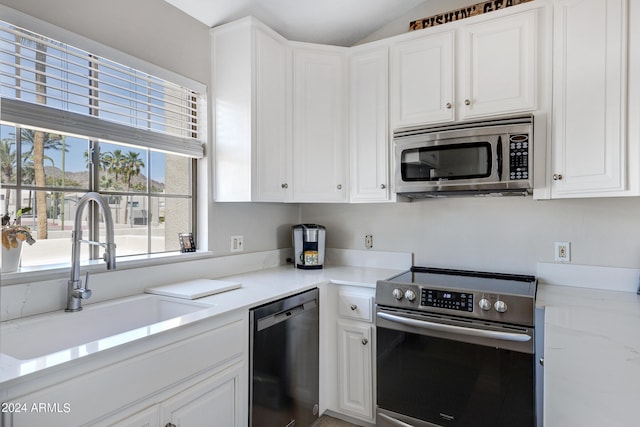 kitchen featuring white cabinets, sink, appliances with stainless steel finishes, and lofted ceiling