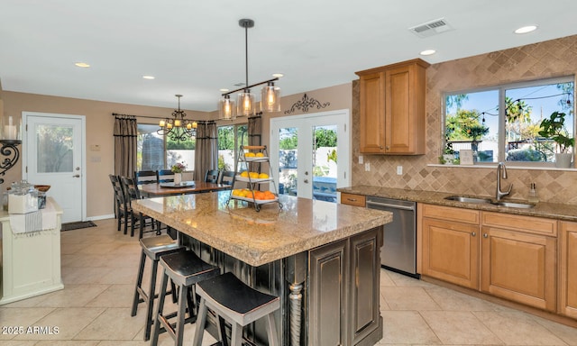 kitchen featuring a breakfast bar, a kitchen island, sink, light stone counters, and dishwasher