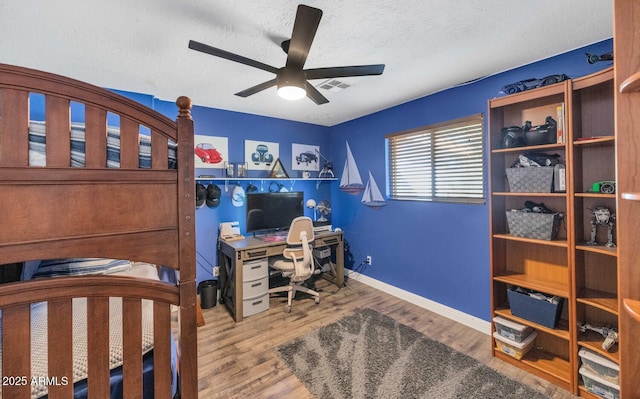 bedroom with a textured ceiling, ceiling fan, and wood-type flooring