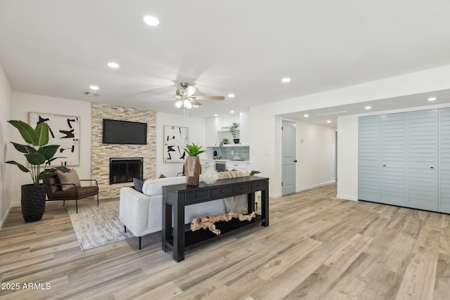 living room featuring ceiling fan, a fireplace, and light hardwood / wood-style floors