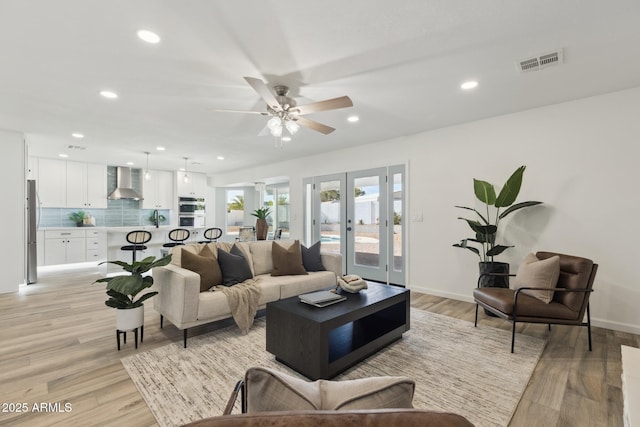 living room featuring sink, light hardwood / wood-style flooring, french doors, and ceiling fan