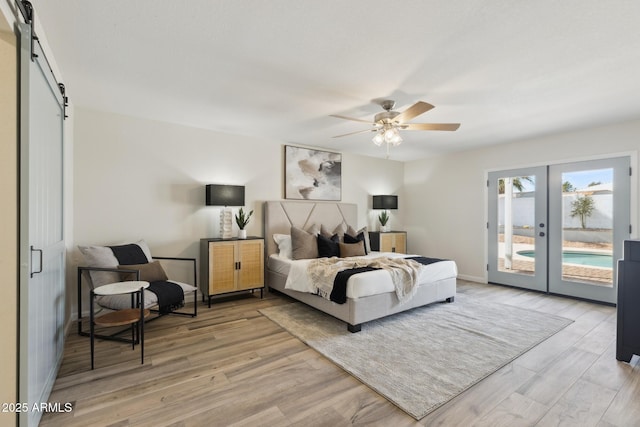 bedroom featuring light hardwood / wood-style flooring, ceiling fan, access to exterior, french doors, and a barn door