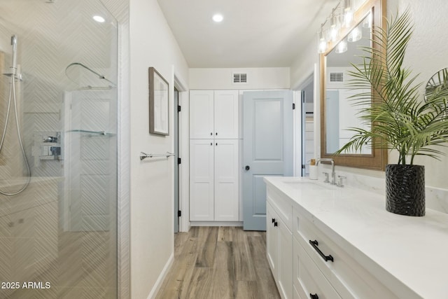 bathroom featuring vanity, hardwood / wood-style flooring, and tiled shower