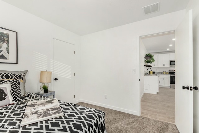 bedroom with sink and light carpet