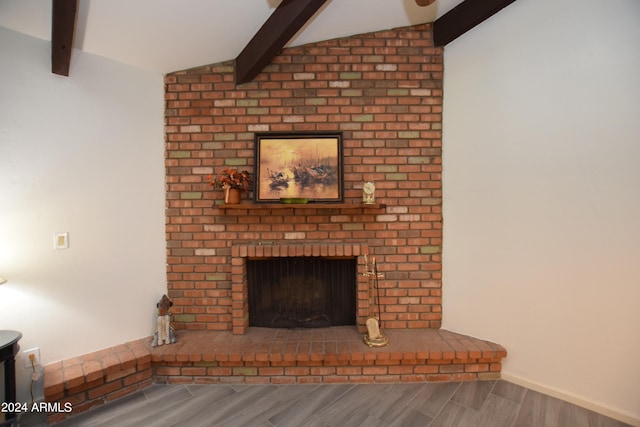 unfurnished living room featuring a fireplace, vaulted ceiling with beams, and hardwood / wood-style floors