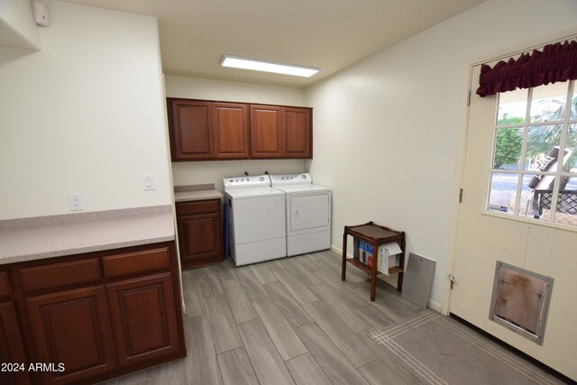 washroom featuring cabinets, light hardwood / wood-style floors, and washer and clothes dryer