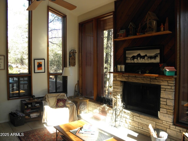 living room with a stone fireplace and ceiling fan