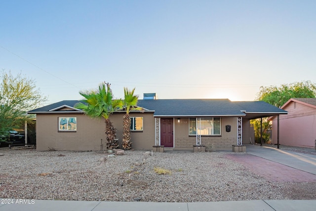 ranch-style house with an attached carport, brick siding, and driveway