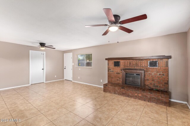 unfurnished living room with ceiling fan, light tile patterned flooring, and a brick fireplace