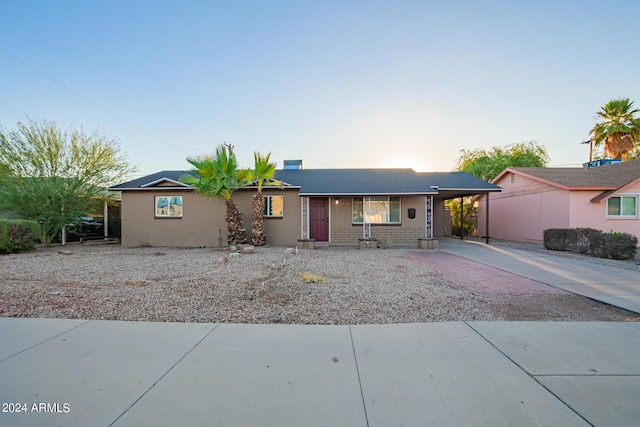 ranch-style house with a carport, brick siding, and concrete driveway