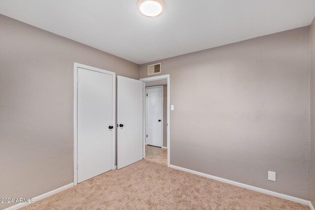 unfurnished bedroom with a closet and light colored carpet