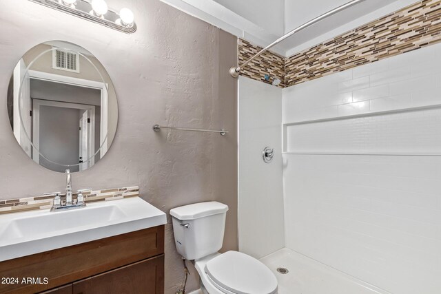 bathroom with toilet, decorative backsplash, a shower, and vanity