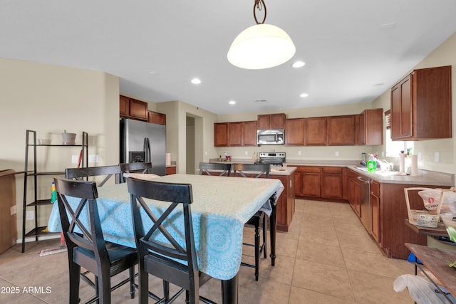 kitchen with light tile patterned floors, stainless steel appliances, brown cabinetry, and light countertops