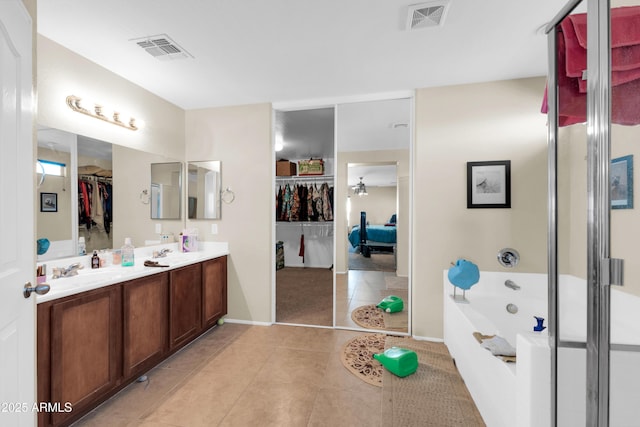 bathroom featuring a garden tub, visible vents, tile patterned floors, and a sink