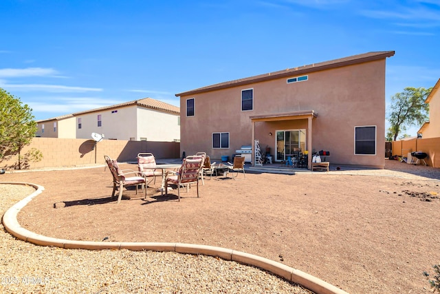 rear view of property with a fenced backyard, stucco siding, a fire pit, and a patio