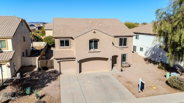 view of front of property with fence, a tiled roof, concrete driveway, stucco siding, and a garage