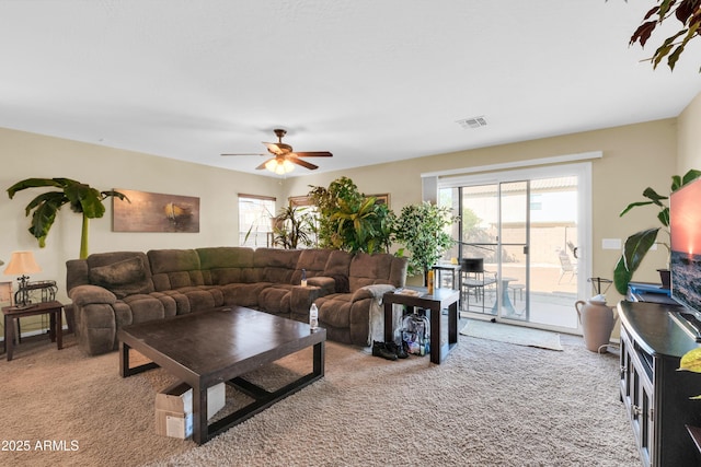 living area featuring visible vents, light carpet, and ceiling fan