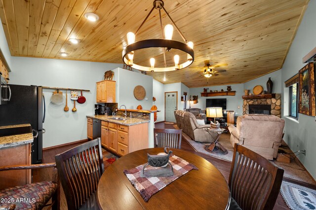 dining space featuring sink, a fireplace, wood ceiling, ceiling fan with notable chandelier, and ornamental molding