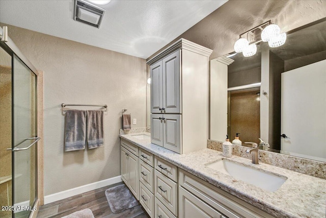 full bath featuring visible vents, a sink, wood finished floors, and a stall shower