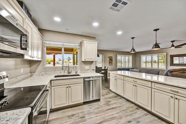 kitchen featuring a sink, light wood-style floors, stainless steel appliances, open floor plan, and visible vents