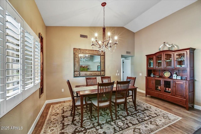 dining room featuring visible vents, a chandelier, vaulted ceiling, and light wood-type flooring