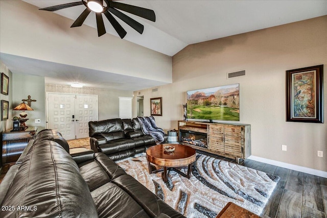 living room with a ceiling fan, visible vents, vaulted ceiling, wood finished floors, and baseboards