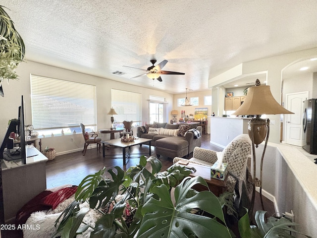 living area featuring visible vents, baseboards, ceiling fan, wood finished floors, and a textured ceiling