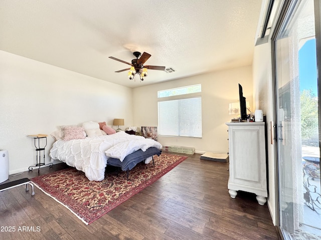 bedroom with visible vents, baseboards, dark wood-style floors, a textured ceiling, and a ceiling fan