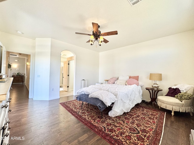 bedroom featuring visible vents, baseboards, wood finished floors, arched walkways, and a ceiling fan