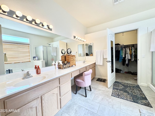 full bathroom with double vanity, a shower stall, and a sink