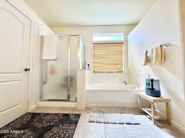 bathroom featuring a shower stall, a garden tub, and baseboards