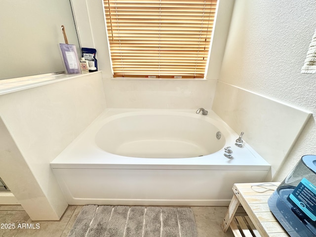 bathroom with vanity, a garden tub, and a textured wall