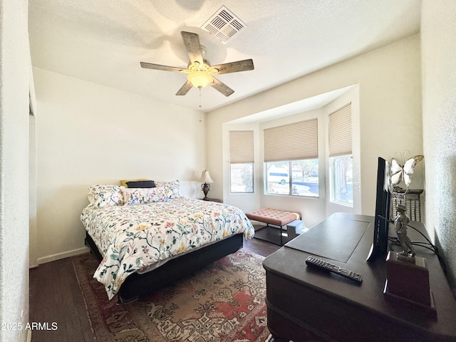 bedroom featuring ceiling fan, visible vents, baseboards, and dark wood finished floors