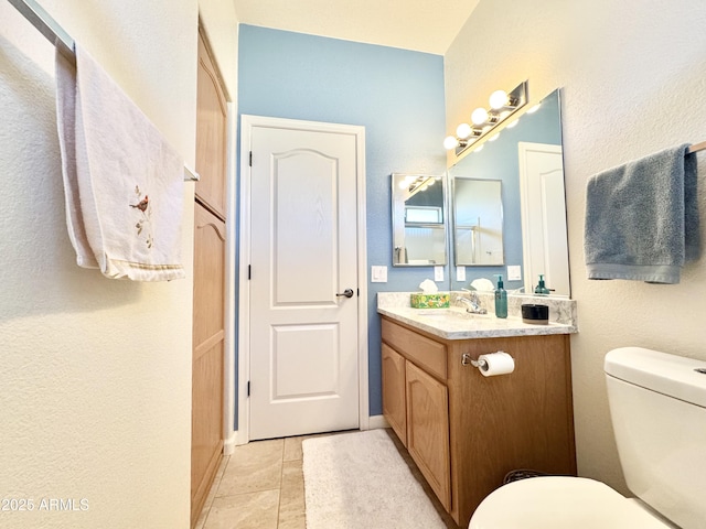 bathroom featuring toilet, vanity, and tile patterned flooring