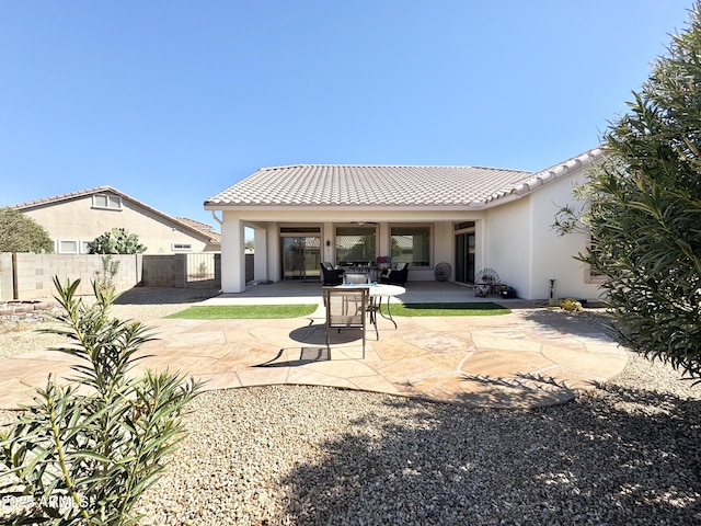 back of house featuring a tile roof, stucco siding, fence, and a patio