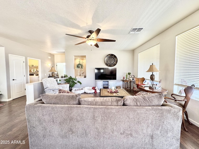 living area featuring dark wood finished floors, a ceiling fan, visible vents, and a textured ceiling