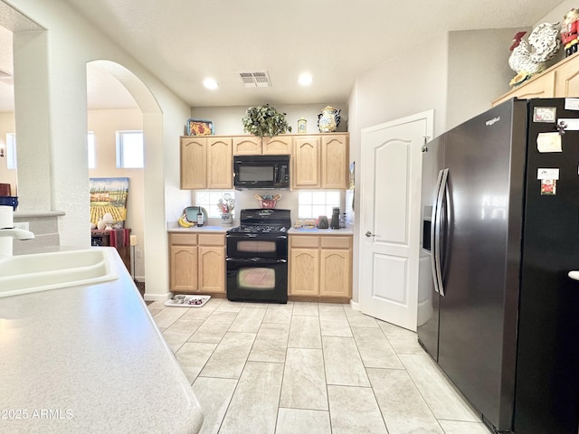 kitchen featuring light brown cabinets, visible vents, arched walkways, a sink, and black appliances