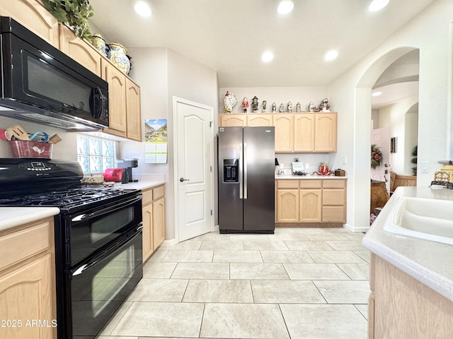 kitchen with light brown cabinets, black appliances, and light countertops