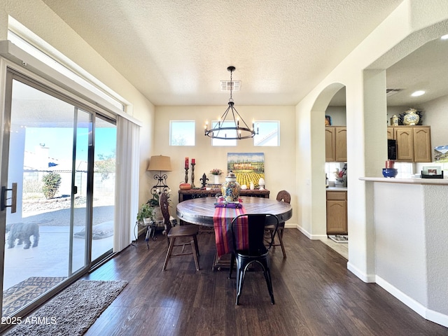 dining room with a notable chandelier, visible vents, baseboards, and dark wood-style floors