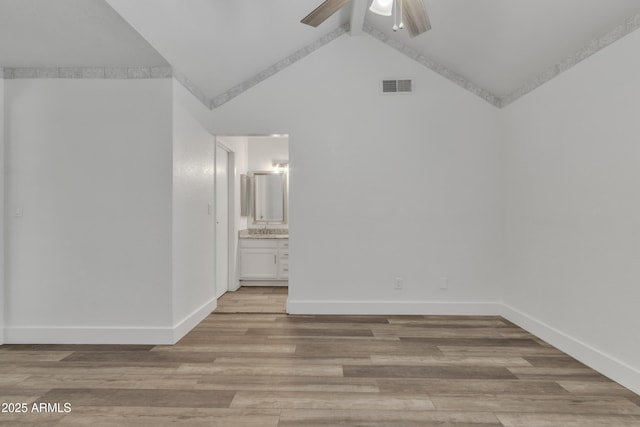 unfurnished room featuring ceiling fan, light wood-style flooring, visible vents, baseboards, and vaulted ceiling