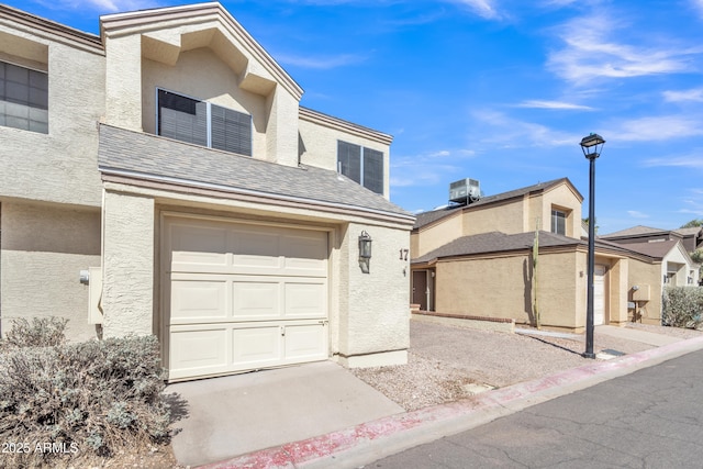 multi unit property featuring central air condition unit, roof with shingles, a garage, and stucco siding